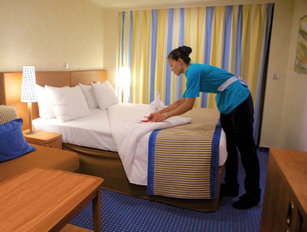 Carnival staff member cleaning and folding bed sheets.