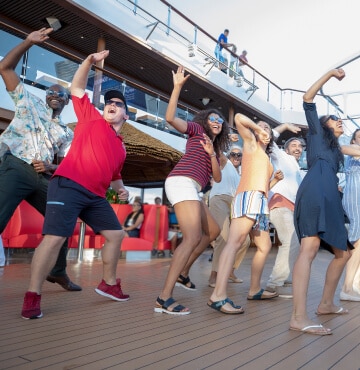 Carnival staff and cruise-goers dancing on the deck enjoying themselves.